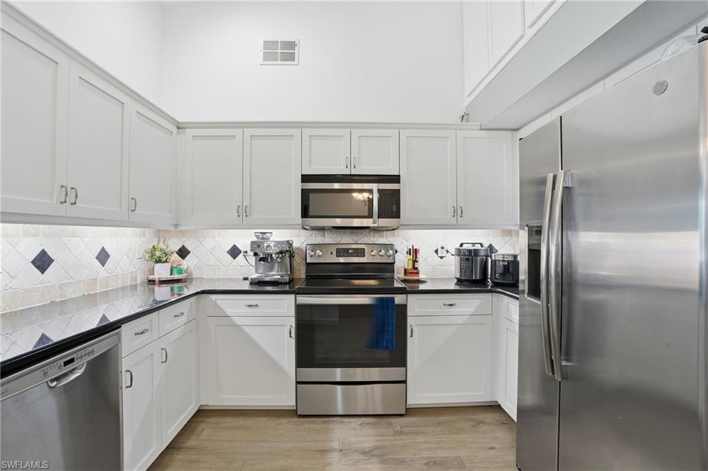 272 Johnnycake Drive Naples, FL 34110 - Photo 8 of 33 a kitchen with granite countertop a refrigerator stove and microwave