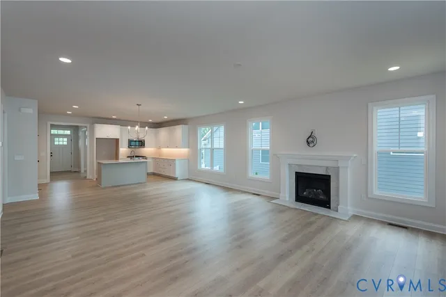 a view of an empty room and a kitchen with wooden floor and a fireplace
