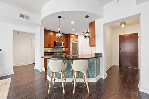 a kitchen with stainless steel appliances kitchen island granite countertop a table chairs in it and wooden floors