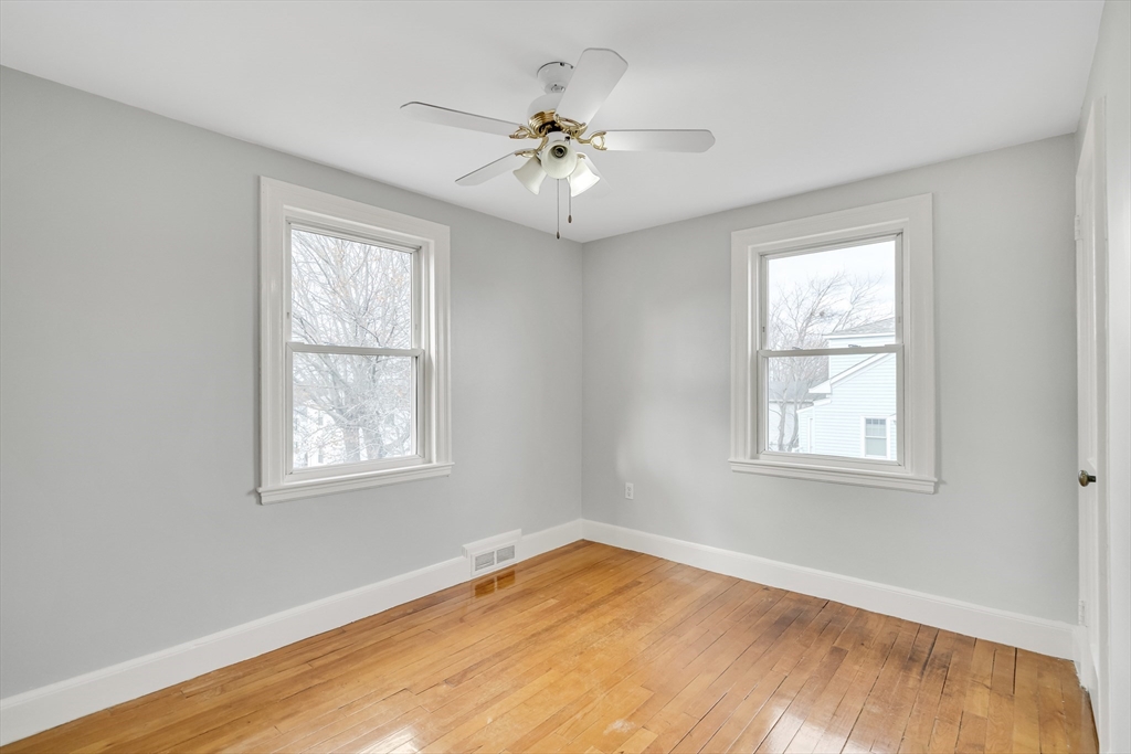 23 Weeks Avenue Boston, MA 02131 - Photo 23 of 34 an empty room with wooden floor chandelier fan and windows