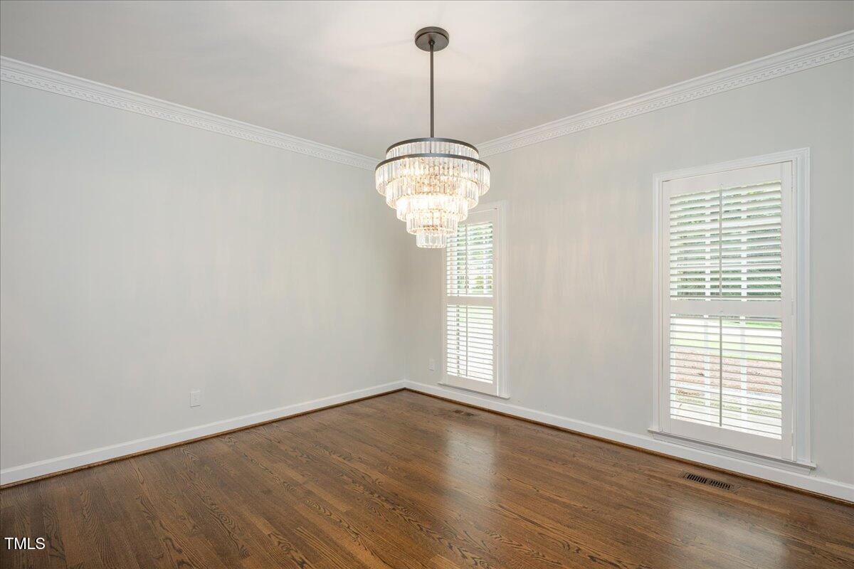 9228 Oneal Road Raleigh, NC 27613 - Photo 25 of 45 an empty room with wooden floor chandelier and windows