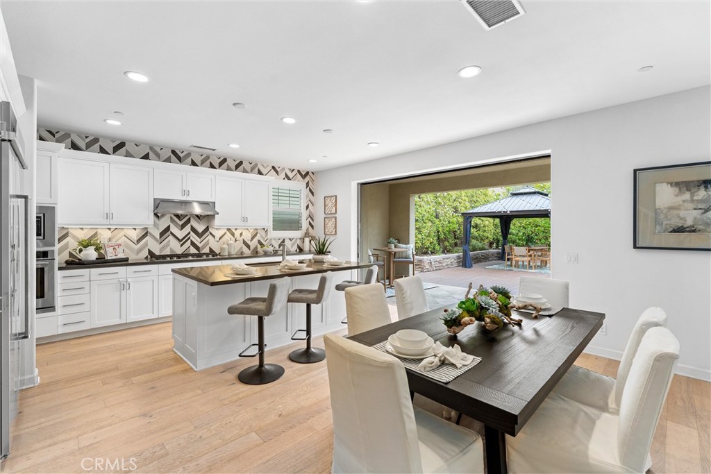 287 Barnes Road Tustin, CA 92782 - Photo 11 of 54 a kitchen with stainless steel appliances kitchen island granite countertop a table chairs in it and wooden floor
