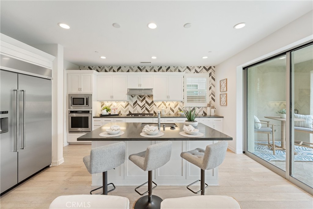 287 Barnes Road Tustin, CA 92782 - Photo 12 of 54 a kitchen with stainless steel appliances kitchen island granite countertop a table and chairs in it