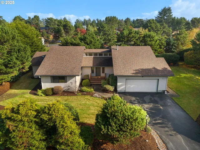 an aerial view of a house with garden space and trees all around