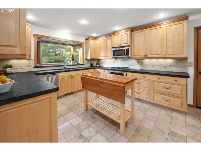 a kitchen with granite countertop cabinets stainless steel appliances a sink and a window
