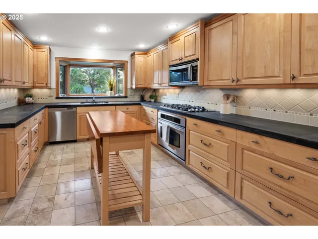 a kitchen with stainless steel appliances granite countertop a stove a sink and a microwave