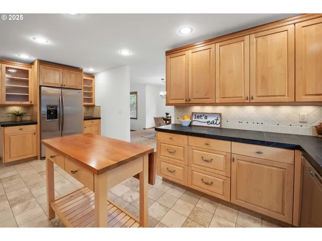 a kitchen with stainless steel appliances granite countertop a refrigerator a sink a stove with white cabinets