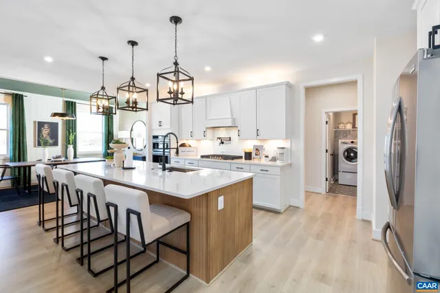 a kitchen with stainless steel appliances kitchen island granite countertop a table chairs and a refrigerator