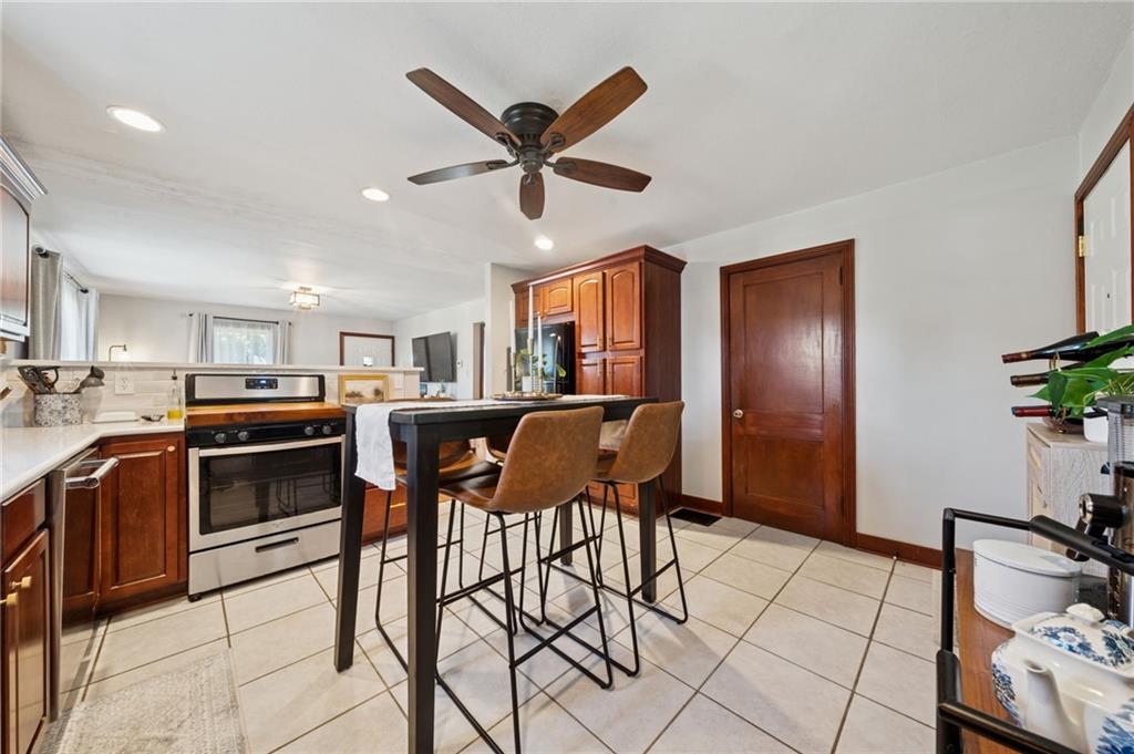 135 Pear Orchard Road Coraopolis, PA 15108 - Photo 14 of 43 a kitchen with stainless steel appliances kitchen island granite countertop a refrigerator a stove a sink with island chairs and wooden floor
