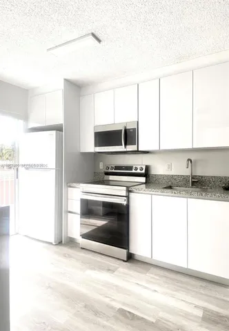 a kitchen with granite countertop a stove a sink and a microwave