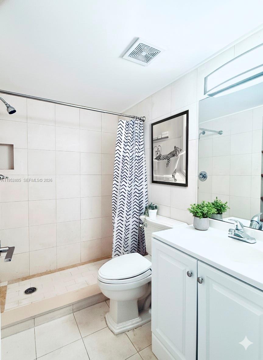 2575 Southwest 27th Avenue, Unit 210 Miami, FL 33133 - Photo 10 of 16 a bathroom with a toilet a sink a mirror a window and vanity