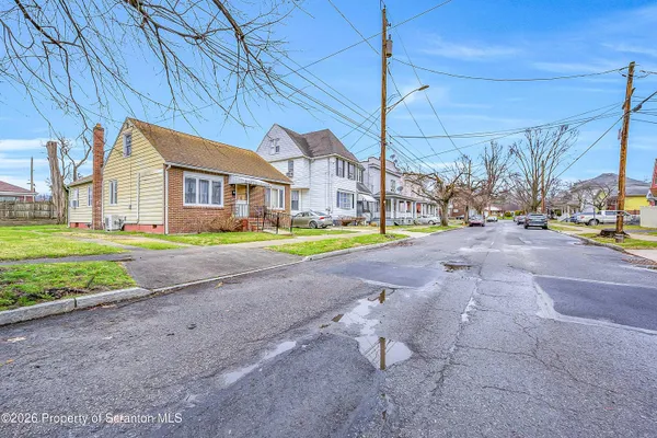 a view of a big house with a big yard and large trees