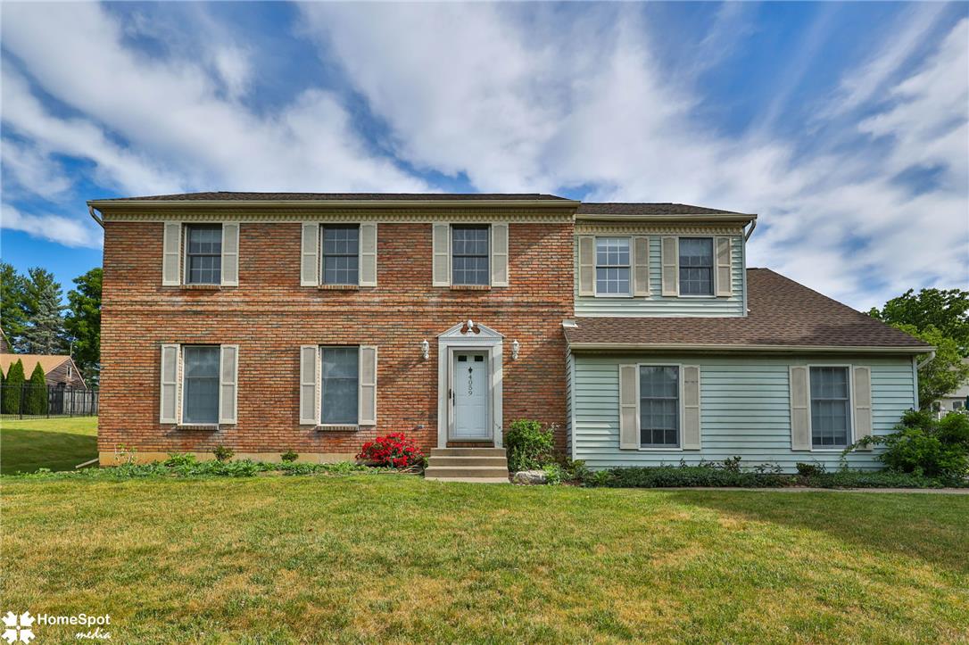 A classic brick and siding residence with ample front lawn offers traditional curb appeal.