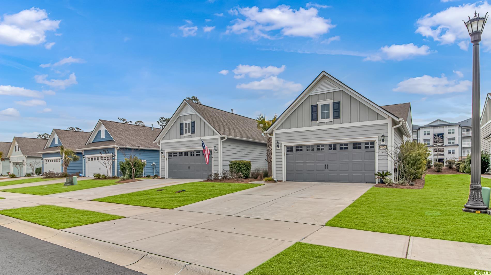 Craftsman inspired home with concrete driveway, board and batten siding, a residential view, and a front lawn