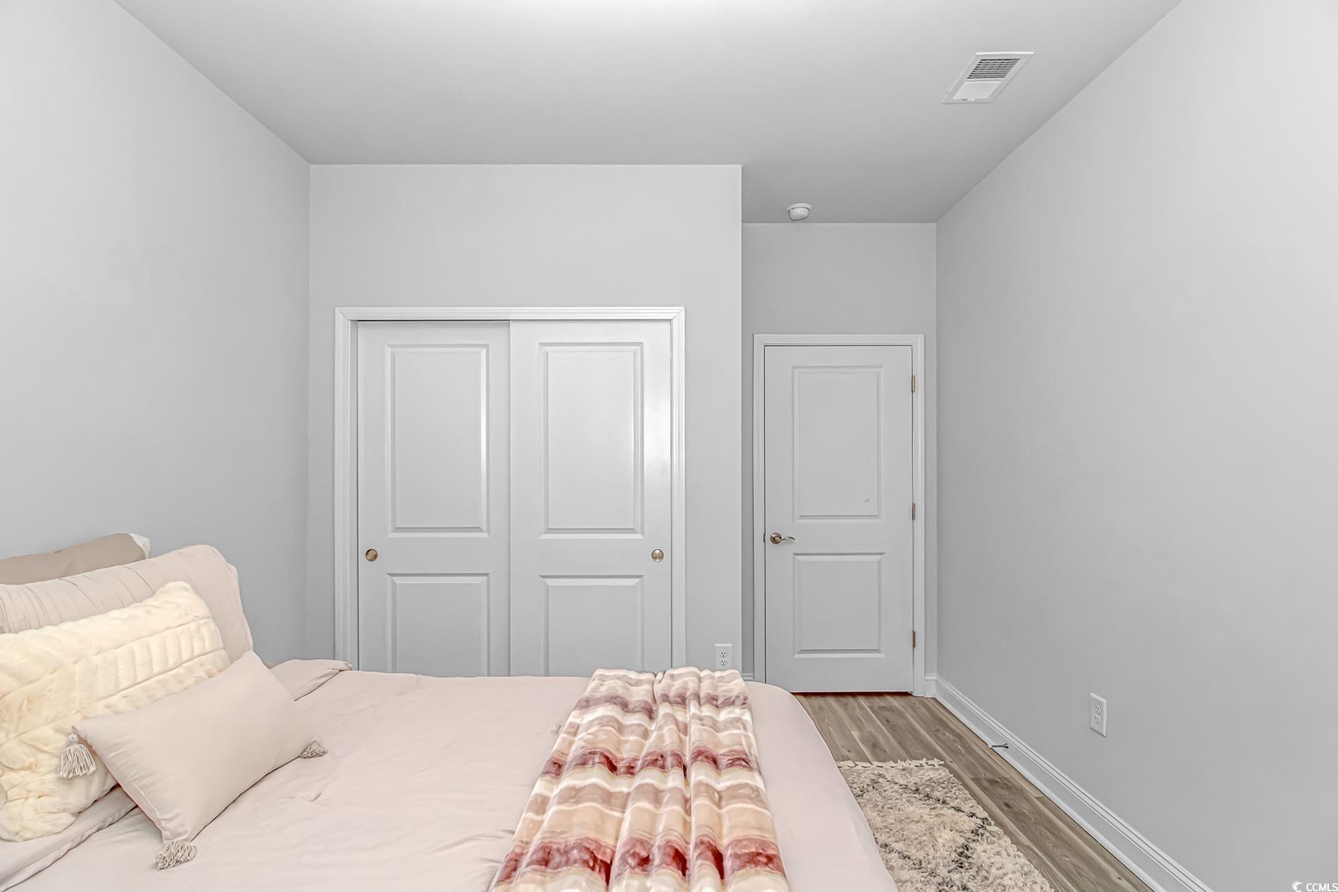 6076 Campanella Street Myrtle Beach, SC 29577 - Photo 18 of 29 Bedroom with baseboards, a closet, visible vents, and wood finished floors
