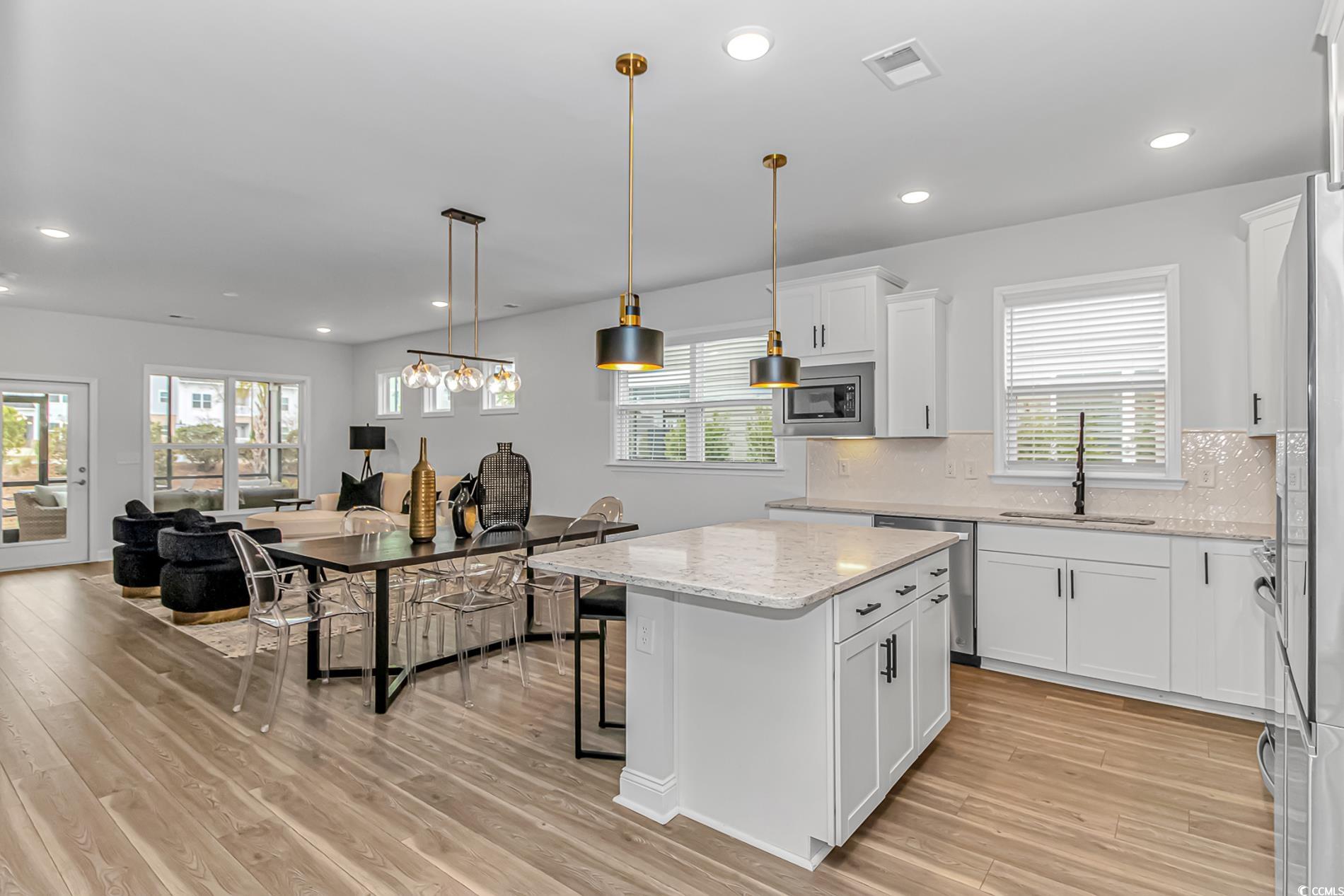 6076 Campanella Street Myrtle Beach, SC 29577 - Photo 4 of 29 Kitchen featuring a sink, stainless steel appliances, visible vents, light wood finished floors, and white cabinetry