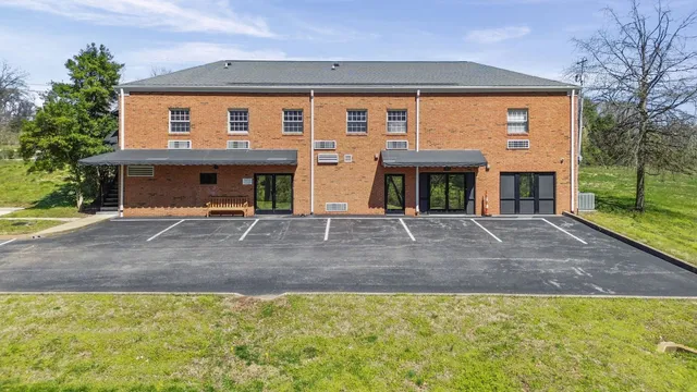 a view of a white house with large windows and a small yard