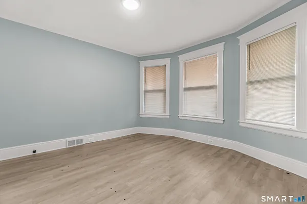 a view of an empty room with wooden floor and a window