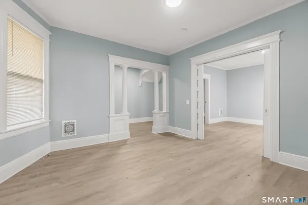 a view of an empty room with wooden floor and a window