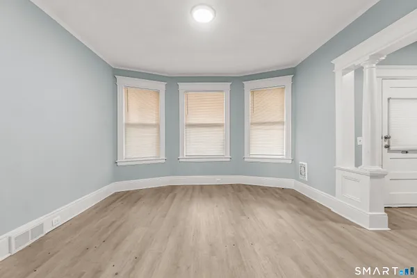 an empty room with wooden floor and windows