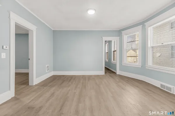 a view of an empty room with wooden floor and a window