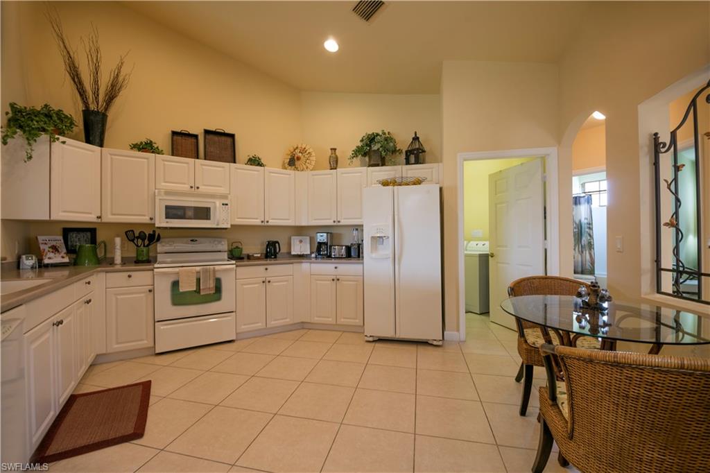 3048 Horizon Lane, Unit 1104 Naples, FL 34109 - Photo 5 of 16 a kitchen with stainless steel appliances kitchen island granite countertop a refrigerator and a stove top oven
