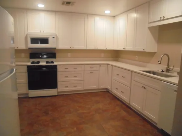 a kitchen with granite countertop white cabinets and stainless steel appliances