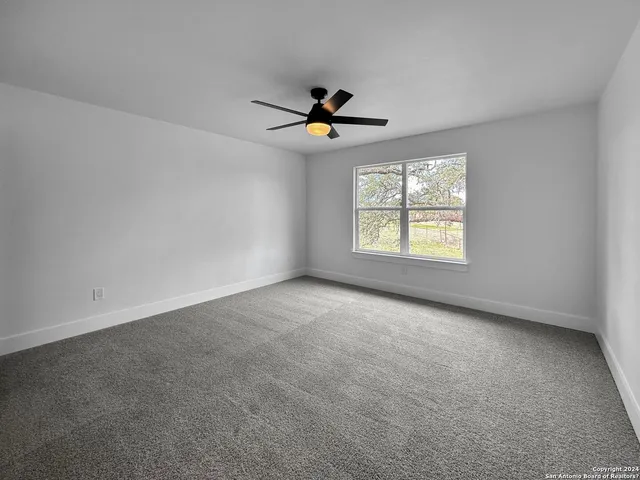 an empty room with windows and chandelier fan