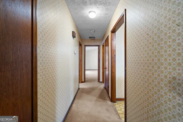 an empty room with windows and chandelier fan