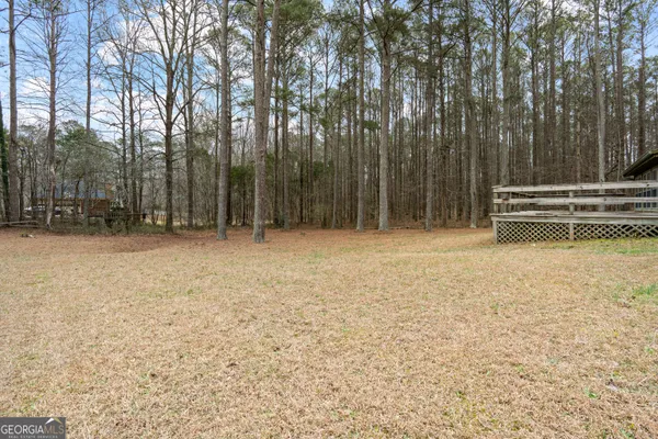a view of backyard with wooden fence and large trees