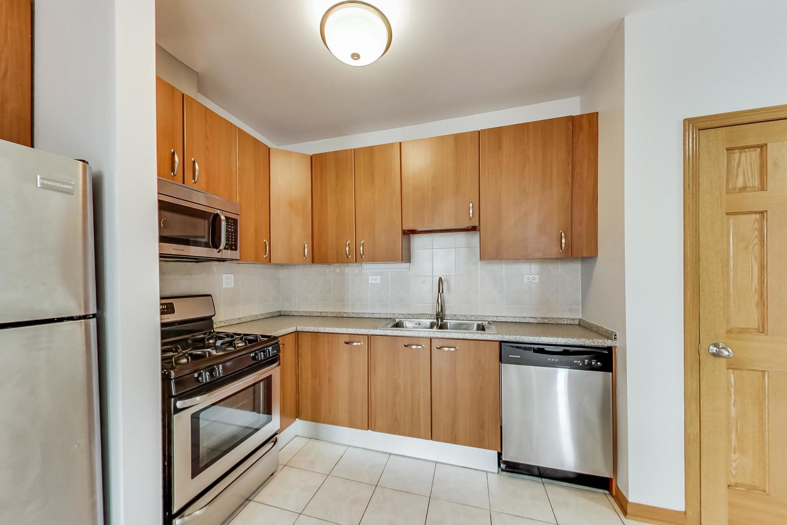 2032 West Division Street, Unit 301N Chicago, IL 60622 - Photo 5 of 12 a kitchen with granite countertop a sink stainless steel appliances and cabinets