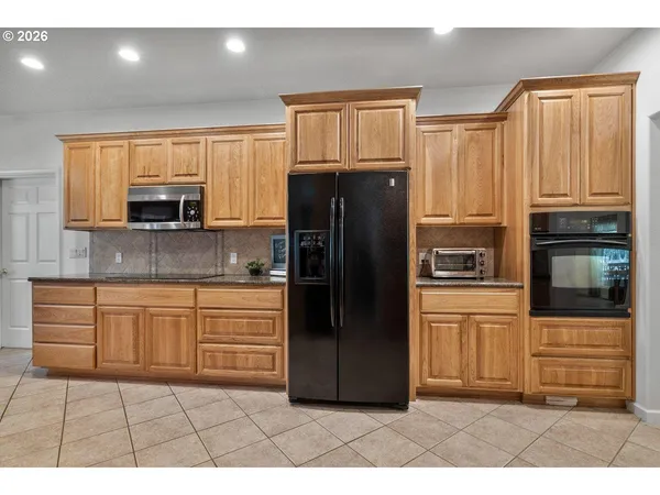 a kitchen with granite countertop a refrigerator and a stove top oven