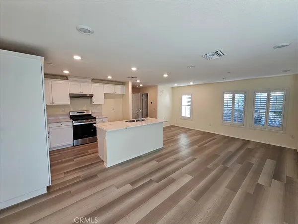 a large kitchen with kitchen island a sink dishwasher a stove and a refrigerator with wooden floor