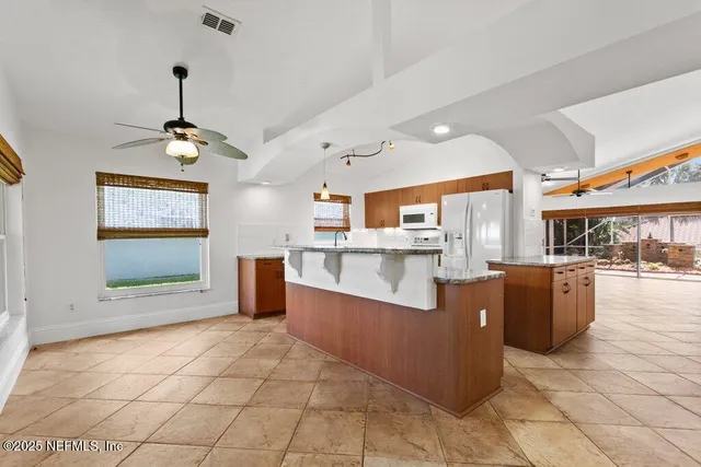 a large kitchen with kitchen island granite countertop a sink a stove counter space and cabinets
