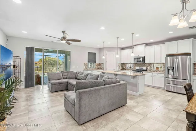 a living room with furniture kitchen view and a chandelier