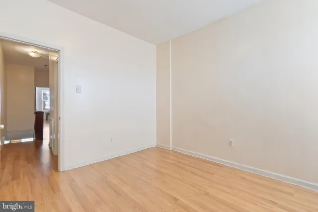 a view of an empty room with wooden floor and a bathroom