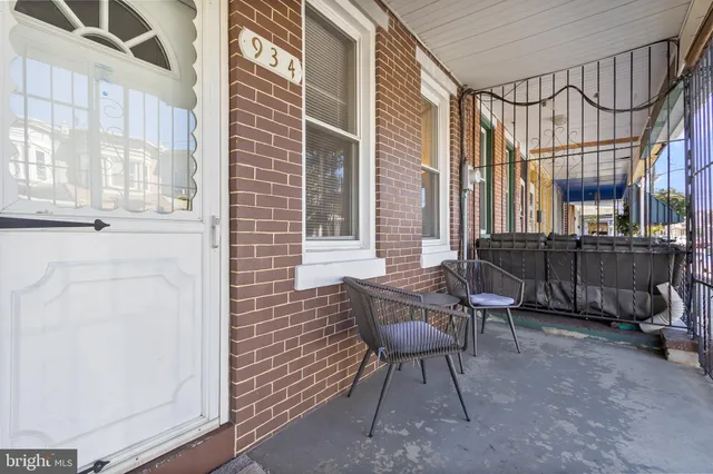 a view of a brick house with chairs and table in a patio