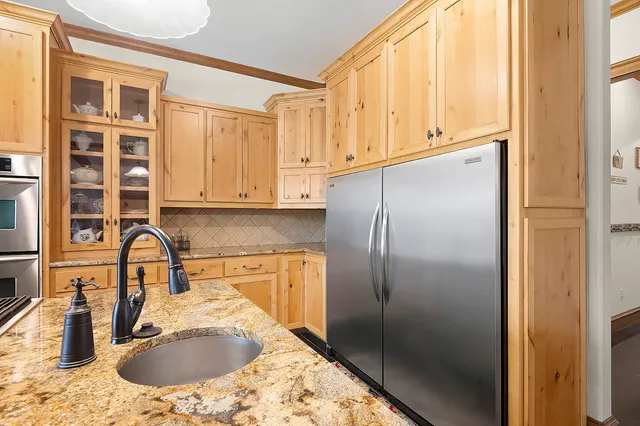 a kitchen with stainless steel appliances granite countertop a sink a refrigerator and a stove