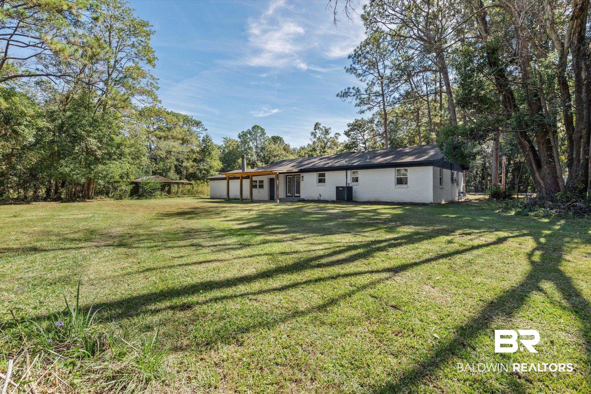 4156 Furman Drive Mobile, AL 36619 - Photo 21 of 24 Rear view of house featuring a lawn, brick siding, and view of scattered trees
