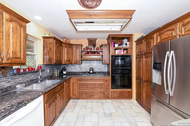 a kitchen with stainless steel appliances granite countertop a refrigerator and a sink
