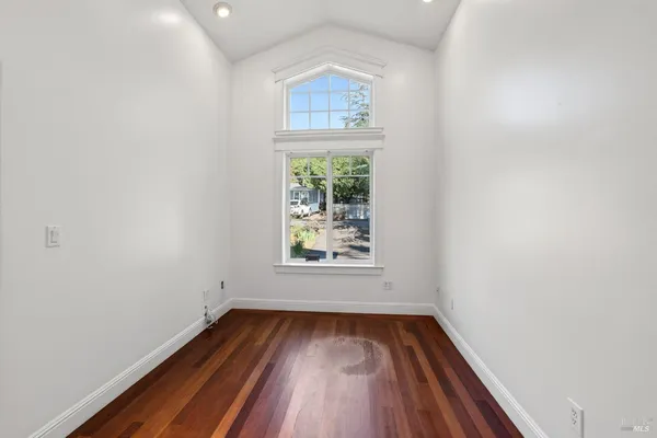 an empty room with wooden floor and windows