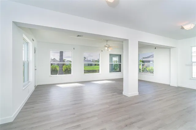 a view of an empty room with wooden floor and a window