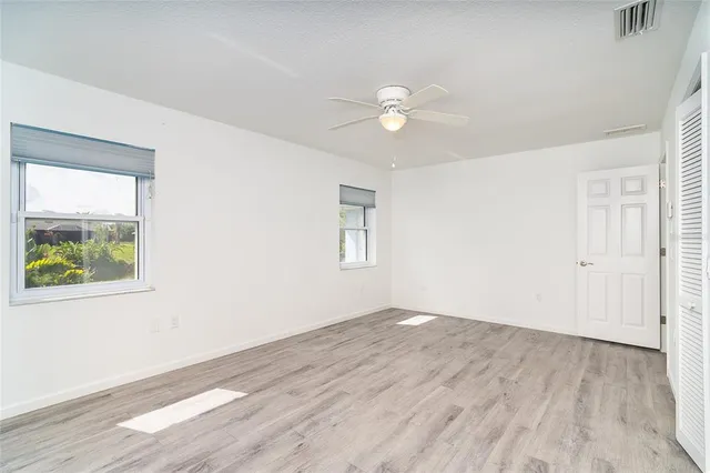 an empty room with wooden floor and windows