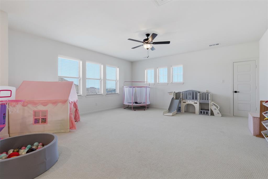 15413 Short Rdg Lane Fort Worth, TX 76008 - Photo 19 of 39 Spacious room with light-colored carpeting, multiple windows with blinds, a ceiling fan with integrated lighting, and a white paneled door with matte black hardware