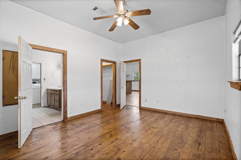 555 Harmon Hills Road, Unit A Dripping Springs, TX 78620 - Photo 4 of 29 A room with wooden flooring and a ceiling fan offers versatile living space.