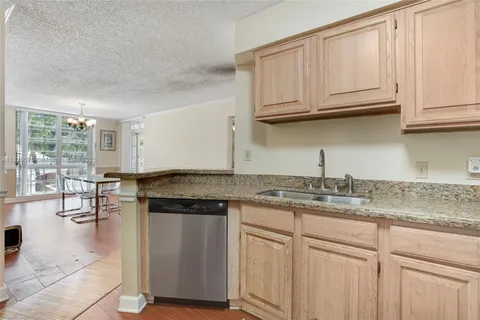 a kitchen with stainless steel appliances granite countertop a stove a sink and white cabinets with wooden floor