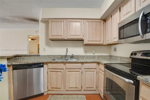 a kitchen with granite countertop a sink stainless steel appliances and cabinets