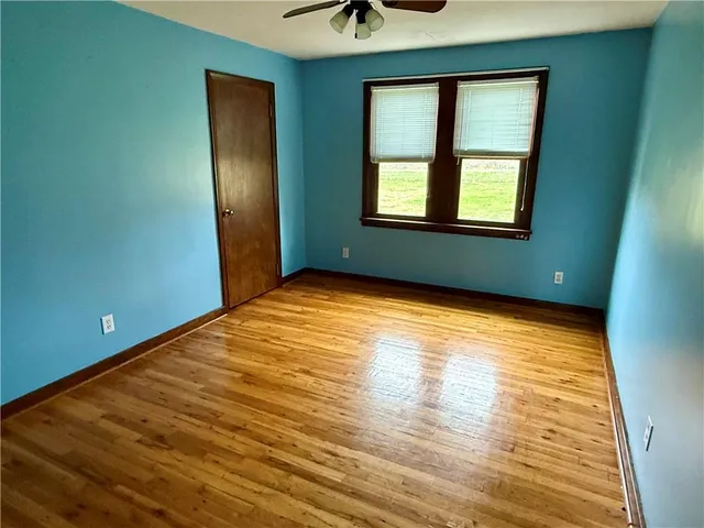 a view of an empty room with window and wooden floor