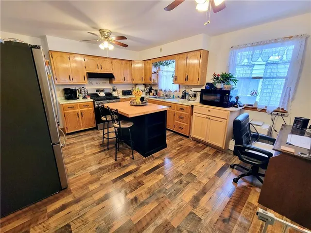 a view of a dining room and kitchen with a table chairs a ceiling fan and a rug