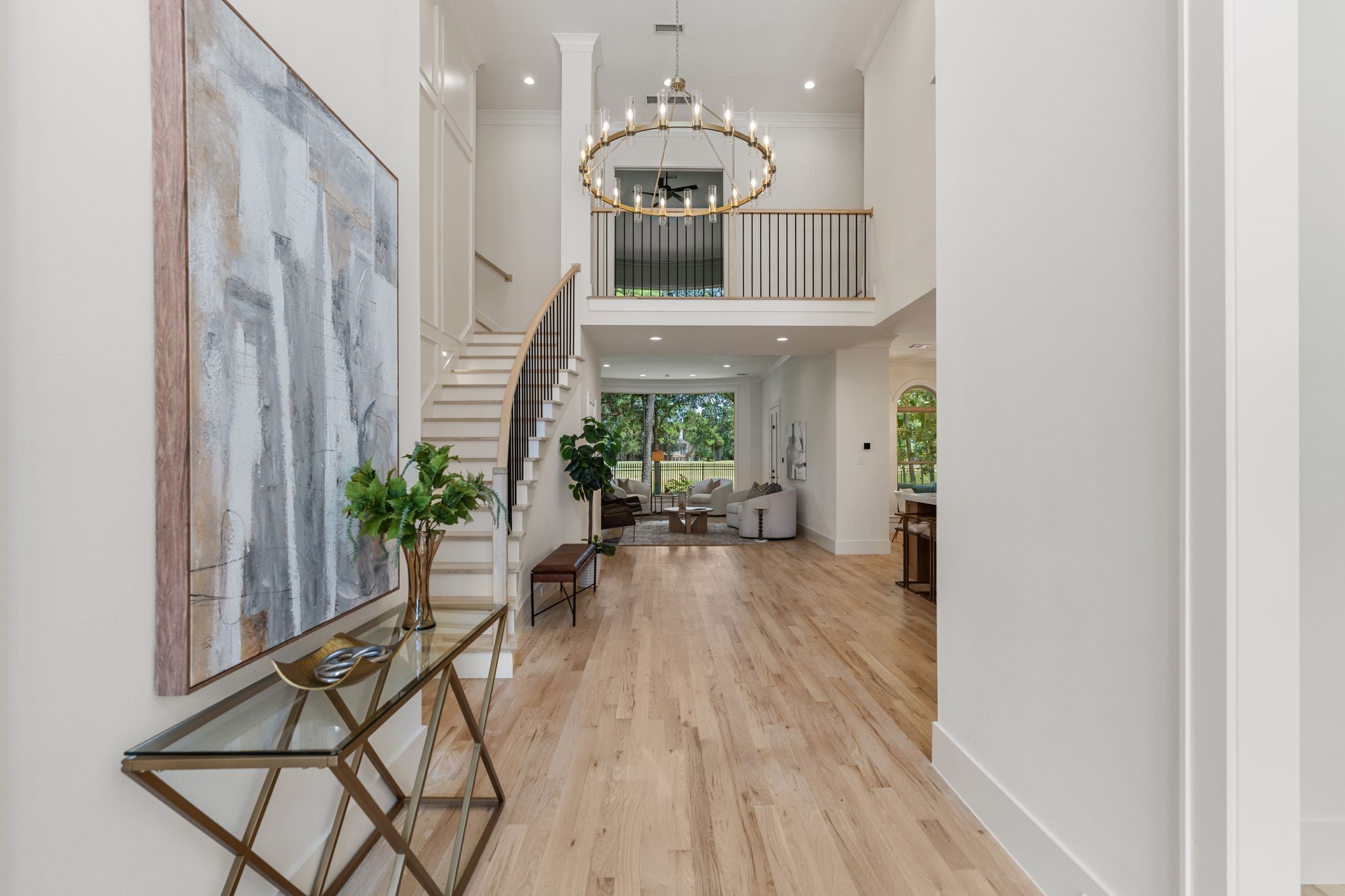 31 Hollymead Drive Spring, TX 77381 - Photo 6 of 50 As you enter this modern, spacious foyer you are greeted with this amazing view of the wooded backyard and golf course. The 2 story ceilings and a grand staircase leads to a bright living area, featuring large windows and incredible views. A contemporary chandelier and light wood flooring enhance the airy ambiance.